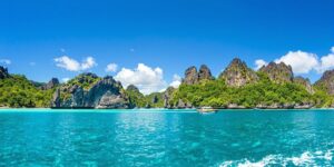 Boat on turquoise waters near green islands.